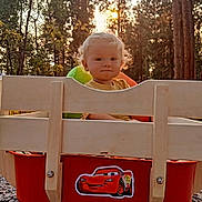 Jade joined the competition — help win amazing prizes! baby, blonde_hair, cartoon_sticker, child, curly_hair, cute, forest, lightning_mcqueen, nature, outdoor, playful, red_wagon, smiling, sunlight, sunset, toddler, toy, trees, wagon, wooden_wagon