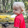 toddler, child, blonde_hair, blue_eyes, red_shirt, forest, stream, water, trees, nature, outdoor, sunlight, daylight, curly_hair, young_child, person, standing, pine_needles, roots, contemplative