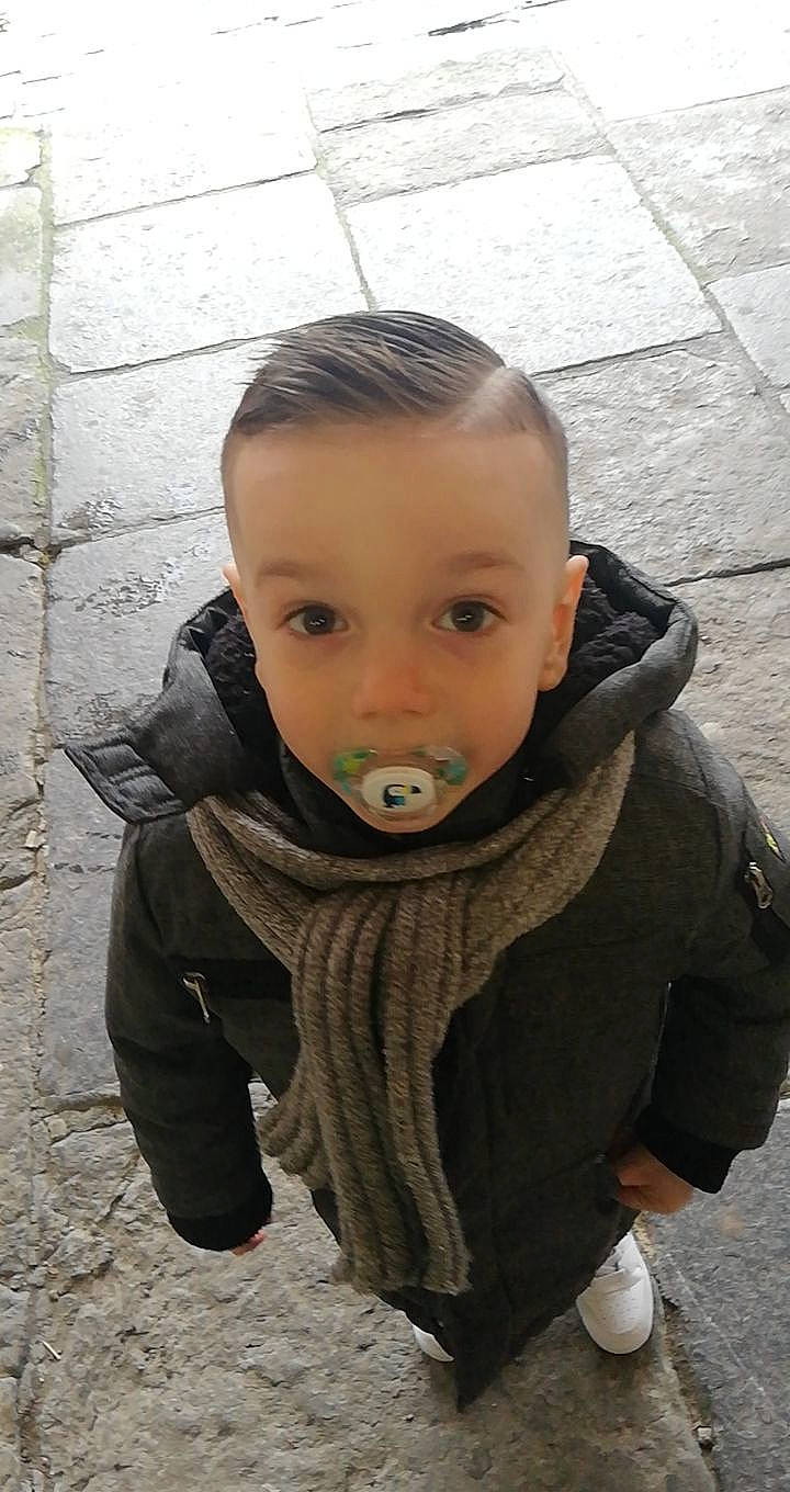 Noë Ruben participe au concours pour gagner de l'argent avec cette photo : baby, baby_toddler_clothing, child, cobblestone, flooring, fur, grass, happy, hoodie, leisure, neck, nose, outerwear, person, personal_protective_equipment, scarf, sitting, sleeve, toddler, tree