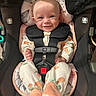 baby, car_seat, smile, infant, onesie, footwear, plush_slippers, straps, safety_harness, child, cute, indoor, seat, person, happy, head, face, apparel, orange, patterned_clothing