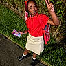 Ava joined the competition — help win amazing prizes! backpack, beads, beige_skirt, black_boots, braided_hair, casual_clothing, child, girl, grass, hedge, holding_packets, night, outdoor, pathway, peace_sign, playful, posing, red_polo_shirt, smiling, winking