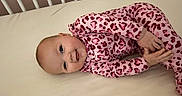Emersyn joined the competition — help win amazing prizes! baby, infant, crib, mattress, pink_clothing, leopard_print, sleepwear, smiling, happy, child, cute, lying_down, indoors, face, head, hand, foot, earring, person, young