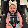 baby, child, car_seat, smiling, headband, bow, straps, infant, cute, happy, rosy_cheeks, denim_outfit, seatbelt, sitting, indoors, person, skin, hand, face, shoulder