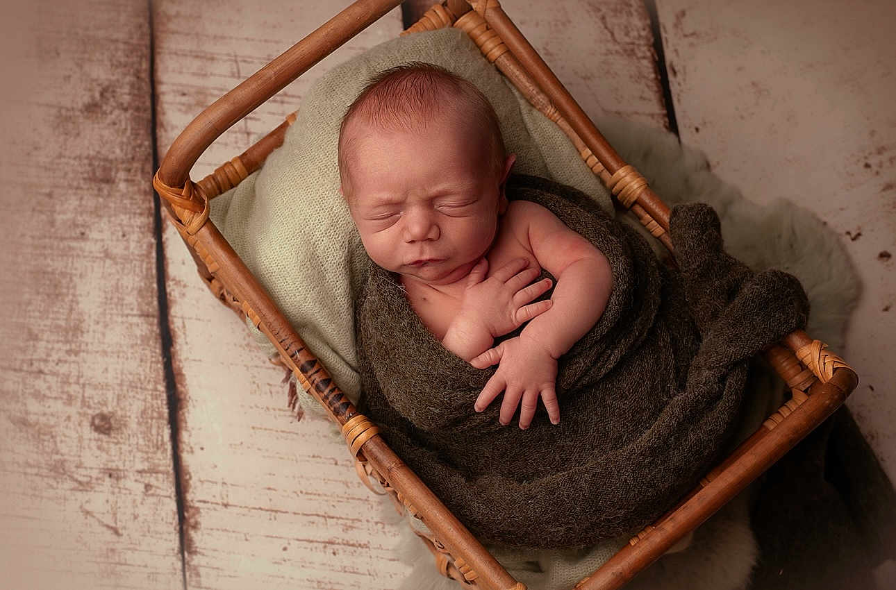 Ysahö participe au concours pour gagner de l'argent avec cette photo : newborn, baby, sleeping, basket, blanket, wooden_floor, wrapped, infant, peaceful, resting, soft_texture, portrait, hands, closed_eyes, cozy, cushion, brown, green, wood, cute