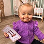Laÿna participe au concours pour gagner de l'argent avec cette photo : baby, child, purple_sweater, pigtails, milestone_card, crib, giraffe_growth_chart, wooden_floor, indoor, smiling, cute, person, portrait, candid, floor, clothing, infant, happy, home, toddler