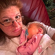 Hazlynn joined the competition — help win amazing prizes! woman, baby, glasses, pacifier, pink_clothing, blanket, indoor, chair, flower, face, person, holding, sleeping, portrait, casual, home, relaxing, closeup, comfort, family