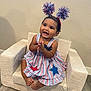 baby, child, clapping, dress, headband, pom_poms, armchair, indoor, floor, wall, happy, smiling, footwearless, star_pattern, red, white, blue, person, portrait, cute