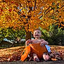 Daniel is registered to the contest to win money with this photo: baby, pumpkin, autumn, fall_leaves, tree, outdoor, smiling, child, nature, seasonal, sunlight, grass, barefoot, sitting, orange, leaf_litter, cute, holiday, festive, happy
