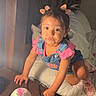 toddler, child, indoor, bed, nightstand, pink, sippy_cup, hair_bows, denim_overalls, pink_shirt, shoes, curly_hair, wood, pillow, blanket, expression, lighting, playful, furniture, cute
