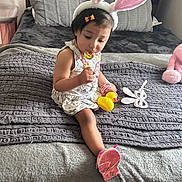 Zelda joined the competition — help win amazing prizes! toddler, child, bunny_ears, lollipop, yellow_rubber_duck, bed, blanket, pillow, toy, bracelet, hair_clip, indoor, cute, pink_shoe, dress, person, soft_toys, playful, cozy, smiling