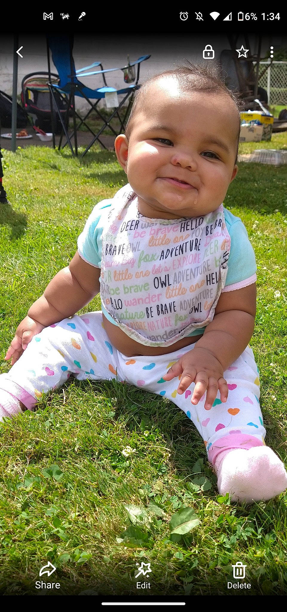 Aria is registered to the contest to win money with this photo: baby, baby_toddler_clothing, cheek, face, facial_expression, finger, grass, green, hair, hairstyle, happy, head, joy, leg, people_in_nature, person, pink, skin, sleeve, smile