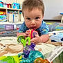 Hudson is registered to the contest to win money with this photo: baby, child, toy, play_mat, colorful, indoor, floor, curious, blue_clothing, soft_toy, plastic_toys, face, hands, crawling, carpet, room, furniture, infant, early_childhood, playtime
