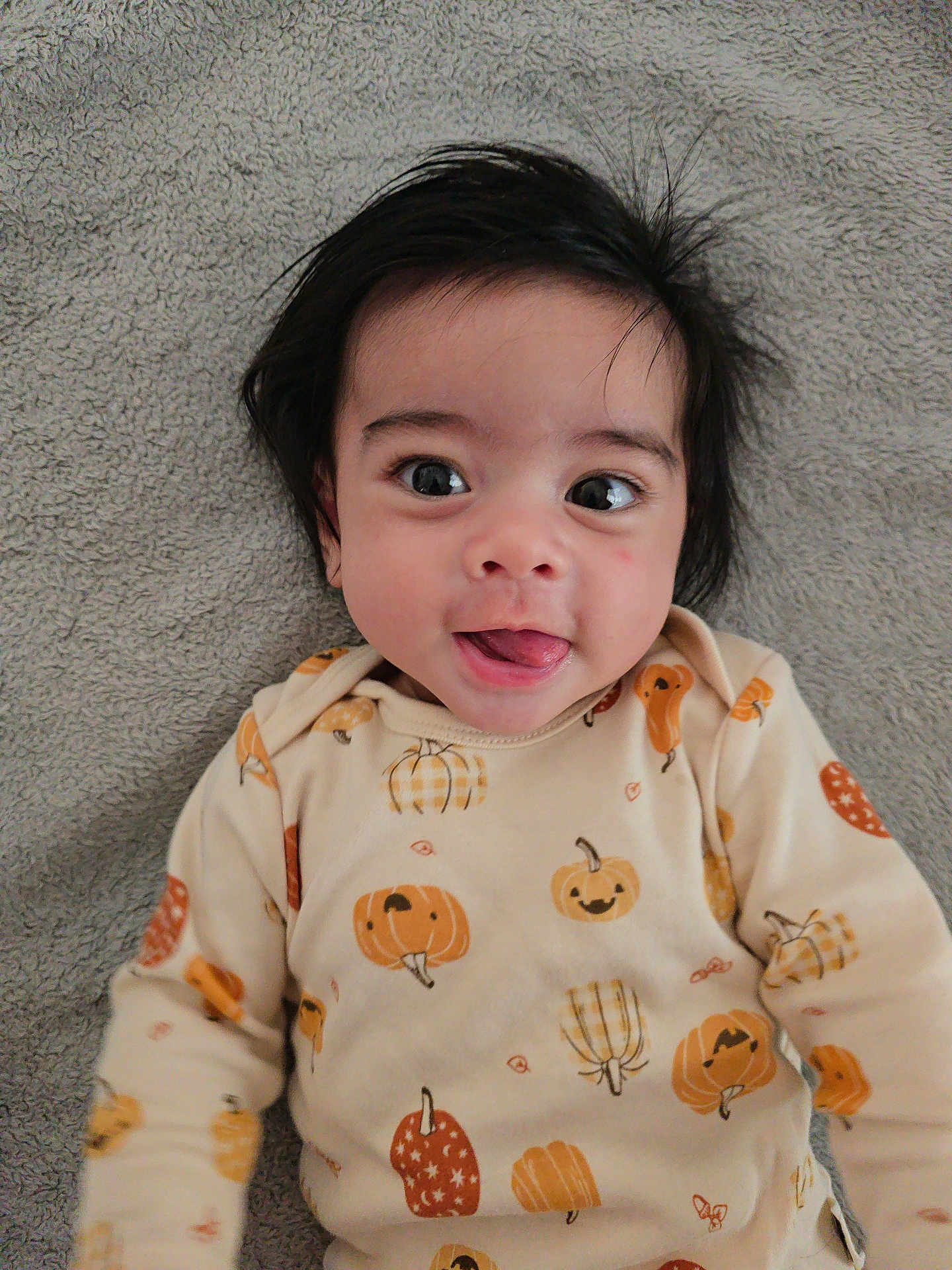 Alexander joined the competition — help win amazing prizes! baby, child, face, tongue, hair, eyes, smile, infant, cute, lying_down, blanket, clothing, pumpkin, fall_theme, playful, portrait, indoors, cozy, happy, young