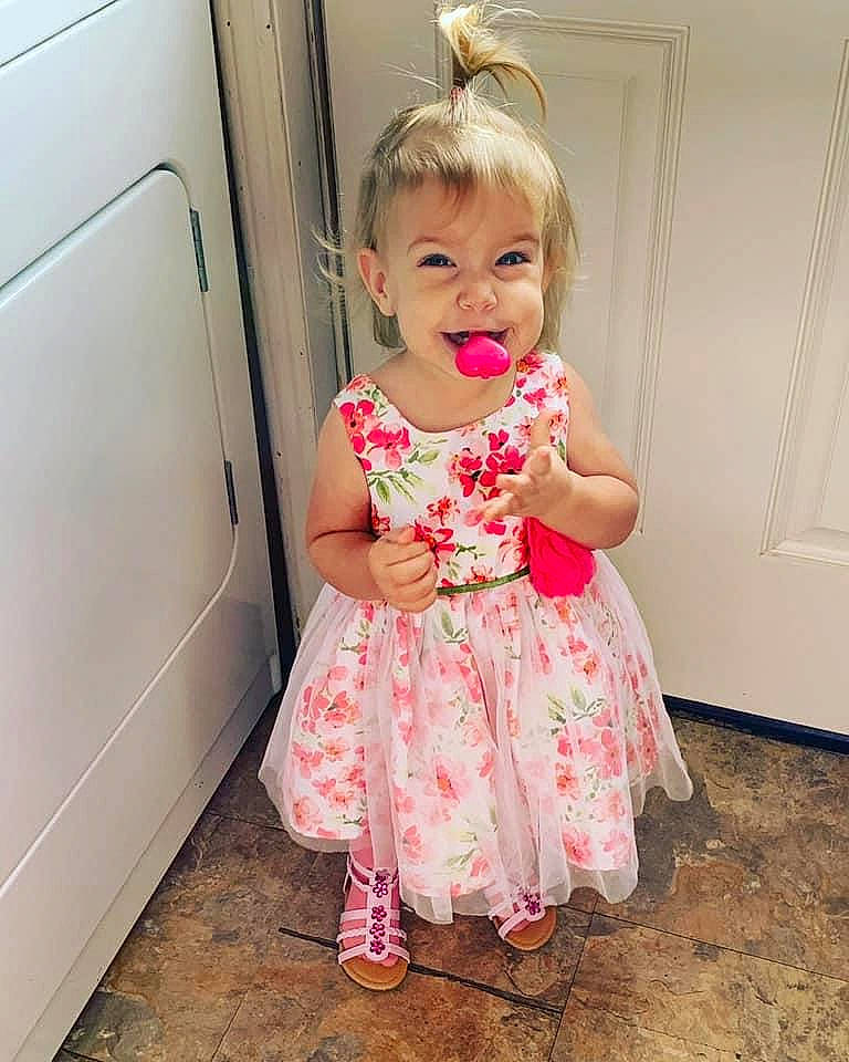 Kaydence is registered to the contest to win money with this photo: baby, baby_toddler_clothing, blond, cheek, child, child_model, clothing, dress, fashion_accessory, pattern, person, pink, room, ruffle, skin, smile, textile, toddler