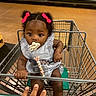 Sarai joined the competition — help win amazing prizes! baby, child, shopping_cart, pacifier, bows, grocery_store, produce, hand, curly_hair, striped_dress, metal_bar, floor, aisle, seat, sitting, infant, cute, holding, indoor, person