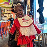 baby, child, smiling, red_clothing, bib, indoor, restaurant, colorful, curtains, table, chair, person_holding_baby, woman, window, flower_pattern, headband, hair_bow, happy, portrait, celebration