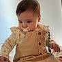 baby, pacifier, beige_clothing, sitting, blanket, pattern, curious, indoor, child, infant, cute, young, portrait, soft_lighting, hands, face, head, long_sleeves, buttons, ruffles