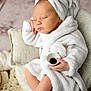 baby, sleeping, robe, towel, cup, hand, foot, blanket, pillow, soft_texture, indoor, relaxation, infant, peaceful, portrait, cozy, child, cute, rest, comfort