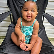 Ava joined the competition — help win amazing prizes! baby, child, smiling, sitting, blue_bows, black_chair, outdoor, concrete, summer_clothing, cute, happy, person, infant, skin, foot, hand, playful, portrait, green_pattern, hair