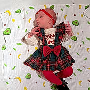 Jade a rejoint le concours — aidez-le/la à gagner de superbes lots ! baby, infant, child, blanket, avocado_pattern, banana_pattern, red_headband, tartan_dress, red_bow, red_tights, black_shoes, lying_down, curious_expression, indoor, soft_texture, cute, small_hands, clothing, portrait, colorful