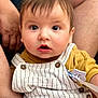 baby, child, closeup, clothing, curious, cute, expression, eyes, face, hands, human, indoor, infant, mustard_shirt, person, portrait, sitting, skin, striped_overall, young