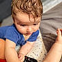 arm, baby, bed, blanket, blue_shirt, candid, child, closeup, curly_hair, expression, focus, hand, indoor, infant, person, remote_control, skin, soft_light, star_pattern, toddler