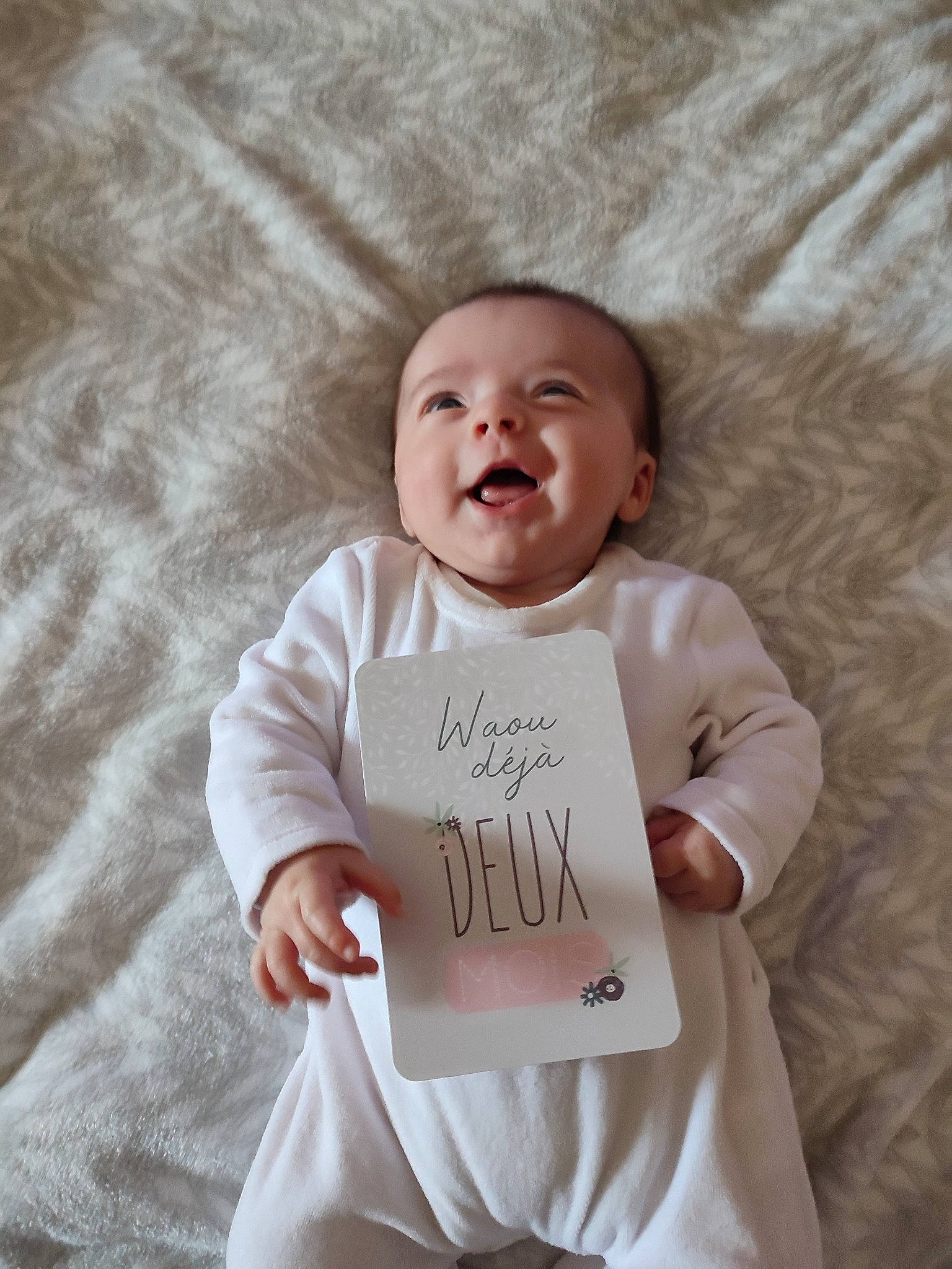 Emma a rejoint le concours — aidez-le/la à gagner de superbes lots ! baby, baby_toddler_clothing, cheek, comfort, face, finger, font, hair, handwriting, happy, head, linens, neck, person, sitting, skin, sleeve, smile, t_shirt, textile
