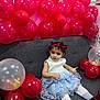 toddler, girl, balloons, red_balloons, transparent_balloons, dress, blue_dress, white_tights, red_boots, headband, red_bow, couch, gray_couch, indoor, celebration, party, child, sitting, curious, festive