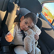 Ikemuefuna is registered to the contest to win money with this photo: toddler, child, car_seat, teddy_bear, stuffed_animal, seatbelt, car_interior, window, sunlight, clothing, cute, portrait, serious_expression, plush, transportation, vehicle, road_trip, seat, young_child, comfort