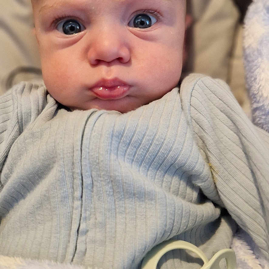 Lennox is registered to the contest to win money with this photo: baby, blanket, bodypart, clothing, couch, face, finger, furniture, hand, happy, head, knitwear, newborn, pants, person, photography, portrait, sweater, sweatshirt, tape