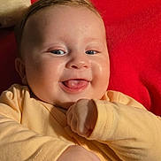 éva a rejoint le concours — aidez-le/la à gagner de superbes lots ! baby, smiling, tongue_out, yellow_clothing, red_cushion, braided_pillow, indoors, cute, happy, infant, chubby_cheeks, face, person, closeup, portrait, hand, pacifier_clip, soft_lighting, skin, cozy