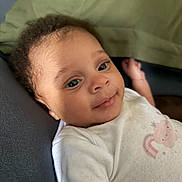 Journee is registered to the contest to win money with this photo: baby, infant, child, curly_hair, white_onesie, pink_cloud, rainbow, smile, face, eyes, skin, couch, cushion, relaxed, portrait, indoor, cute, young_child, person, closeup