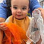 Jack joined the competition — help win amazing prizes! baby, child, smiling, face, person, hands, fabric, orange, white, blue_shirt, indoor, window, door, holding, cute, playful, happy, closeup, bib, long_hair