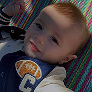 Alonzo is registered to the contest to win money with this photo: baby, child, smile, face, portrait, shadow, colorful_mat, clothing, jacket, infant, cute, playful, lying_down, young_child, closeup, happy, expression, light, texture, casual_wear