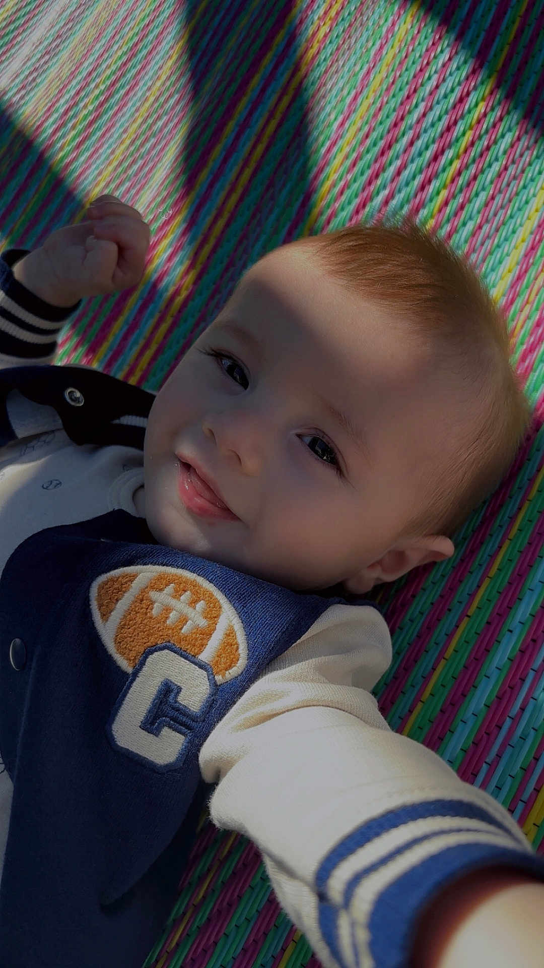 Alonzo is registered to the contest to win money with this photo: baby, child, smile, face, portrait, shadow, colorful_mat, clothing, jacket, infant, cute, playful, lying_down, young_child, closeup, happy, expression, light, texture, casual_wear