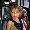 child, car_seat, curly_hair, messy_face, red_stains, popsicle, car_interior, seatbelt, window, sunlight, serious_expression, young_child, summer_clothing, toddler, seat_headrest, car_window, skin, face, person, sitting