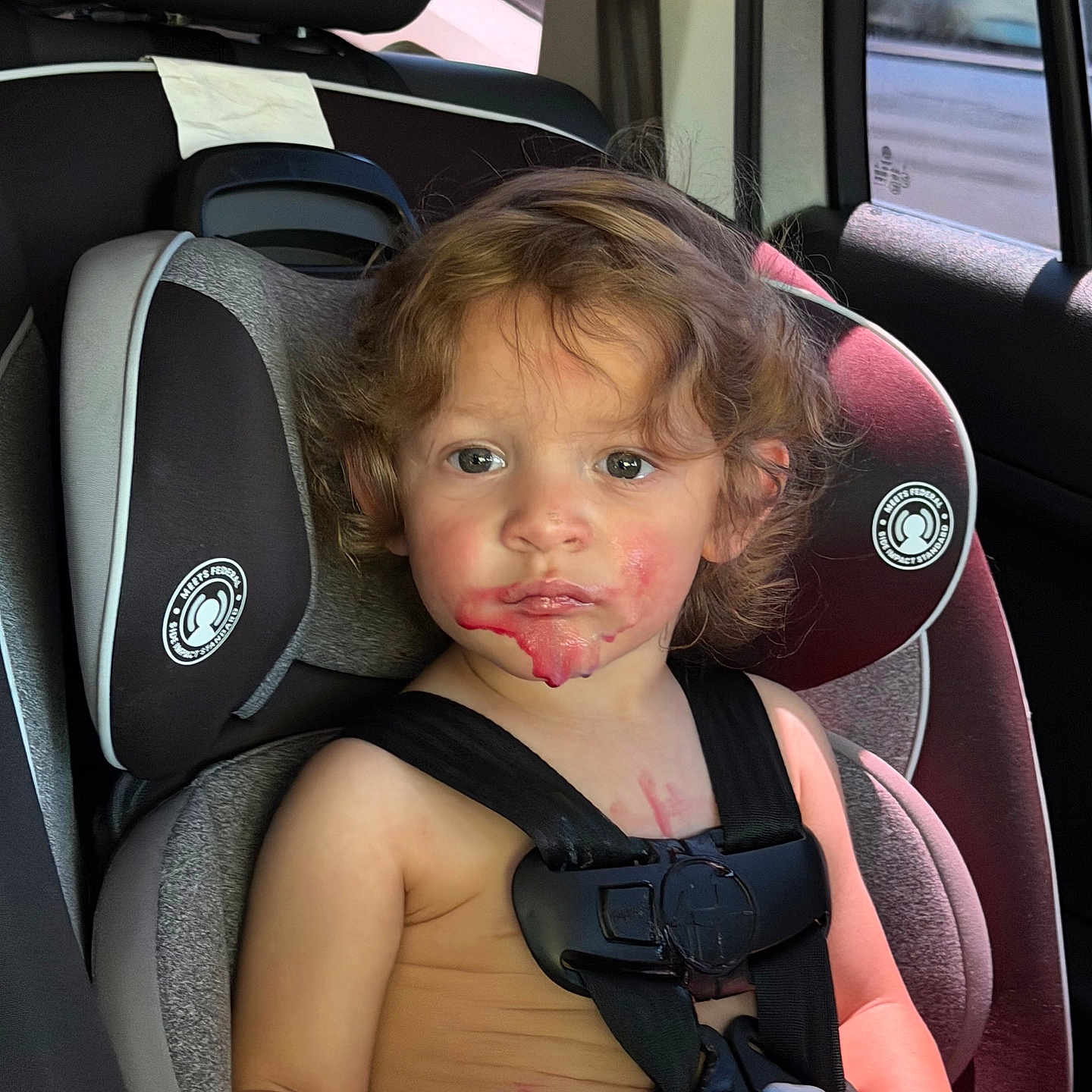 Kairo joined the competition — help win amazing prizes! child, car_seat, curly_hair, messy_face, red_stains, popsicle, car_interior, seatbelt, window, sunlight, serious_expression, young_child, summer_clothing, toddler, seat_headrest, car_window, skin, face, person, sitting