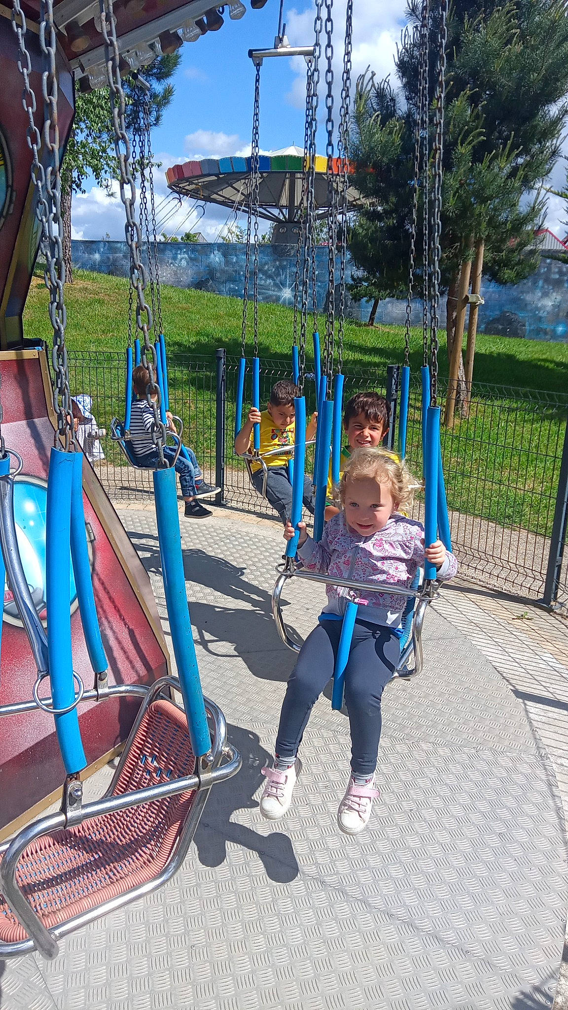 Kimberley a rejoint le concours — aidez-le/la à gagner de superbes lots ! chute, city, electric_blue, fence, fun, grass, human_settlement, joy, leisure, outdoor_play_equipment, person, plant, play, playground, public_space, recreation, sky, summer, swing, toddler