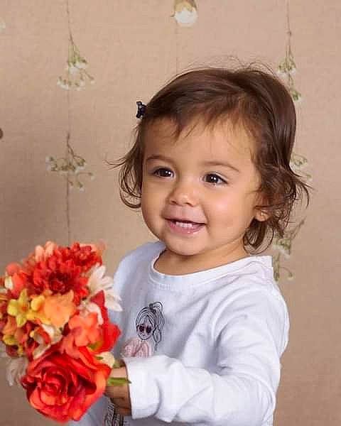 Shaylee is registered to the contest to win money with this photo: baby_toddler_clothing, dress, face, facial_expression, flower, hair, hairstyle, happy, head, iris, joy, person, petal, pink, plant, rose, sleeve, smile, standing, textile