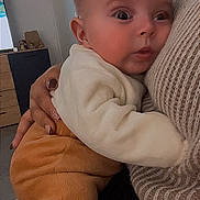 Tiago a rejoint le concours — aidez-le/la à gagner de superbes lots ! baby, infant, child, holding, cuddle, hand, sweater, knit, pants, onesie, close_up, portrait, indoor, living_room, furniture, gaze, big_eyes, skin, cozy, caregiver_hand