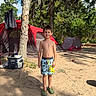 Xayden is registered to the contest to win money with this photo: child, boy, camping, tent, outdoor, forest, trees, sunlight, smile, shorts, sandals, nature, recreation, summer, vacation, greenery, sky, leisure, happy, daytime