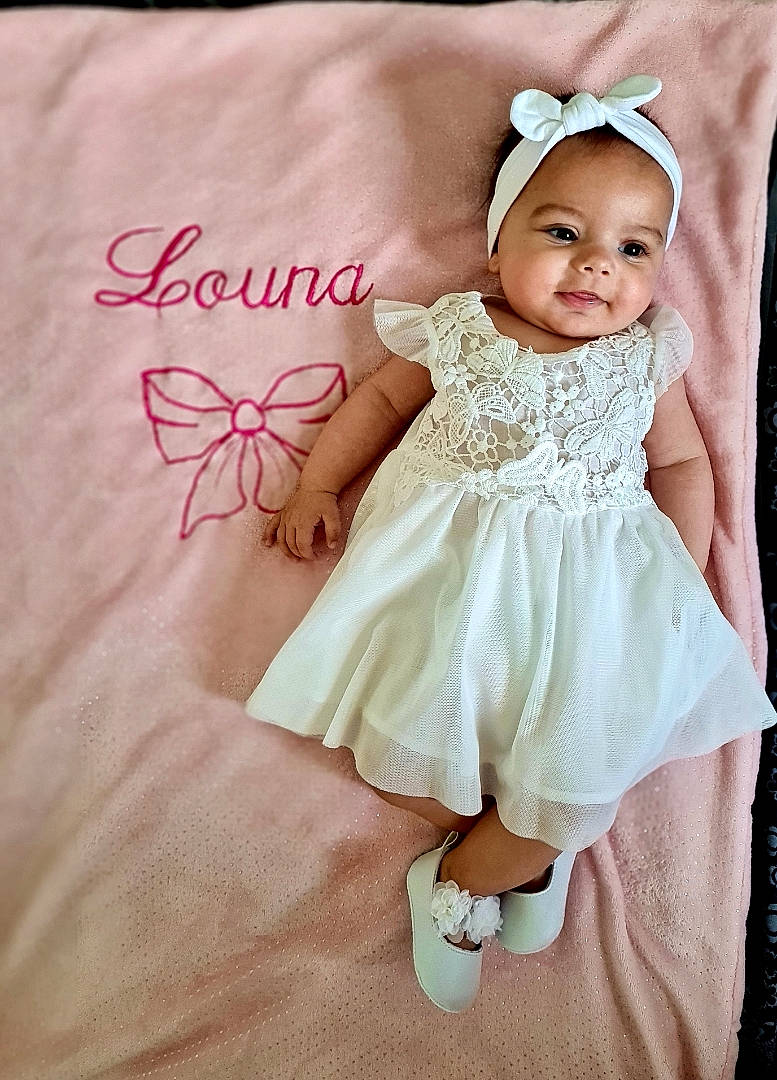 Louna a rejoint le concours — aidez-le/la à gagner de superbes lots ! baby, baby_toddler_clothing, dress, embellishment, eye, face, finger, flash_photography, happy, head, headpiece, iris, pattern, person, pink, pollinator, sleeve, smile, toddler, wedding_ceremony_supply