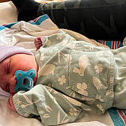 Marleigh is registered to the contest to win money with this photo: baby, newborn, sleeping, pacifier, beanie, hospital_blanket, onesie, mint_color, floral_pattern, swaddled, tiny_hand, hospital_bed, camo_pants, adult_leg, towel, portrait, closeup, peaceful, soft_texture, infant_clothing