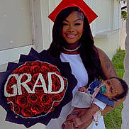 Zariah joined the competition — help win amazing prizes! graduate, baby, woman, red_cap, white_dress, bouquet, roses, flower_arrangement, outdoor, smile, portrait, celebration, person, holding_baby, grass, house, window, tattoo, necklace, pacifier