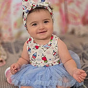 Danelly Anais is registered to the contest to win money with this photo: baby, child, infant, sitting, smiling, portrait, headband, bow, tutu, dress, blue, patterned_clothing, indoors, bedroom, soft_focus, carpet, couch, happy, cute, photography