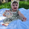Danelly Anais is registered to the contest to win money with this photo: baby, child, smiling, portrait, outdoor, garden, blanket, blue_blanket, headband, bow, dress, floral_dress, sitting, happy, infant, toy_sign, birthday, greenery, bokeh, feet