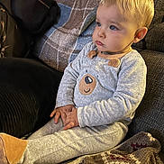 Arthur participe au concours pour gagner de l'argent avec cette photo : toddler, child, pajamas, bear_design, couch, blanket, blue_eyes, blond_hair, indoors, seated, soft_lighting, hands_folded, cozy, expression, face, furniture, home, portrait, warm, casual_clothing