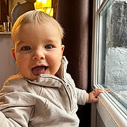 Arthur participe au concours pour gagner de l'argent avec cette photo : baby, blond_hair, child, clothing, curtain, cute, expression, face, hand, happy, home, indoor, light, person, portrait, smiling, toddler, tongue_out, window, zipper