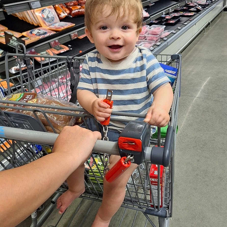 Noah is registered to the contest to win money with this photo: aisle, baby, barefoot, bread, child, floor, food, grocery_store, hand, happy, packaged_meat, person, retail, shopping, shopping_cart, smiling, store, striped_shirt, supermarket, toddler