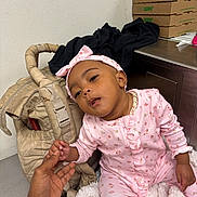 Damarionna joined the competition — help win amazing prizes! baby, child, infant, portrait, pink_clothing, floral_pajamas, headband, bow, smiling, sitting, hand, adult_hand, blanket, baby_carrier, indoor, office, cardboard_boxes, subway_boxes, desk, closeup